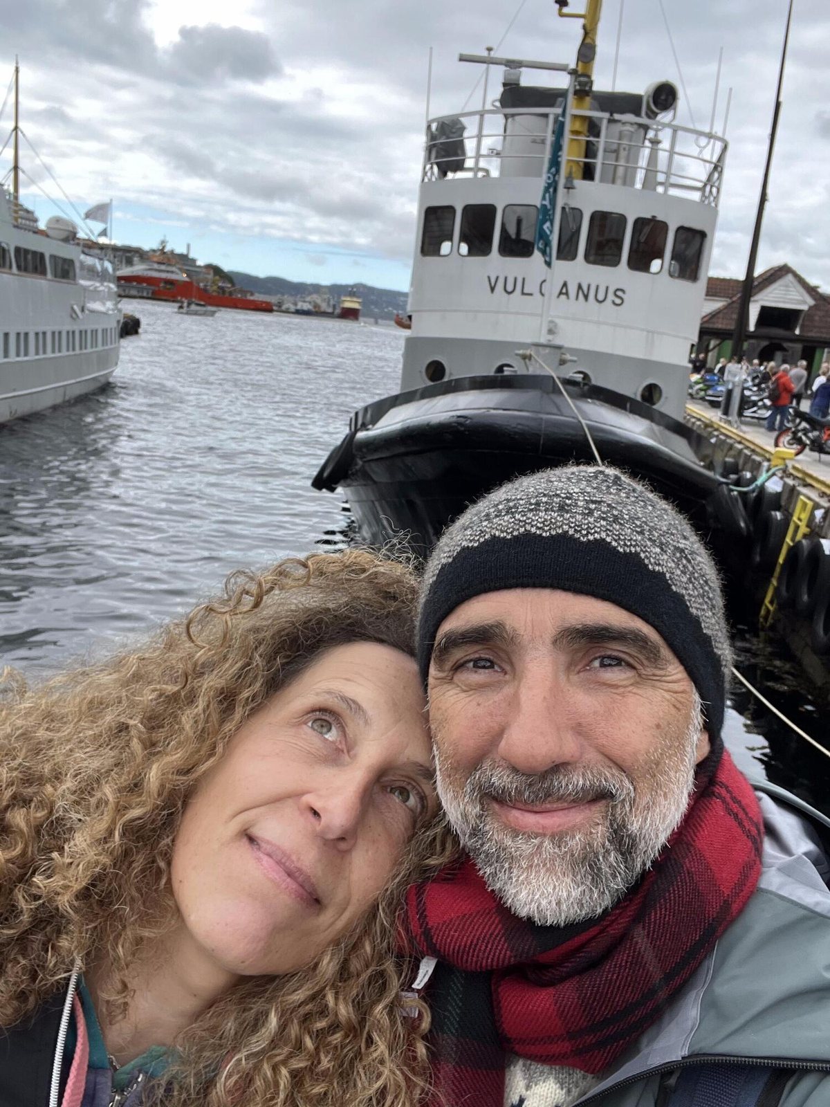 Marina e Sandro abbracciati su una banchina del porto, davanti al rimorchiatore Vulcanus.